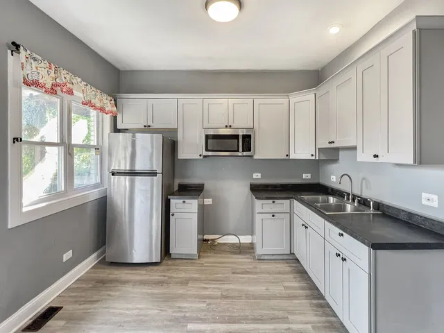 a kitchen with white cabinets stainless steel appliances and wooden floors