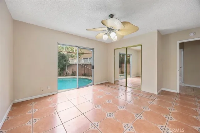 a view of an empty room with a chandelier fan and a window
