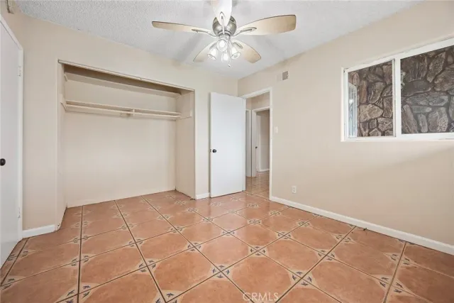 a view of an empty room with window and a ceiling fan