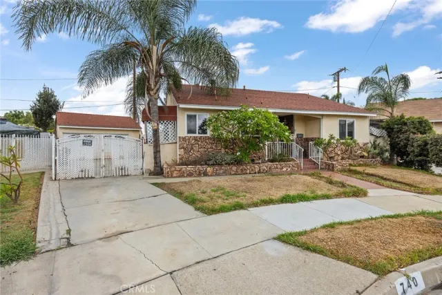 a view of a house with a yard and palm trees