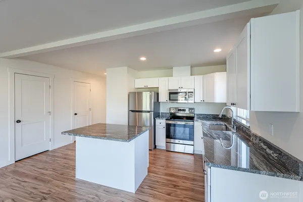 a kitchen with granite countertop a sink stove and microwave