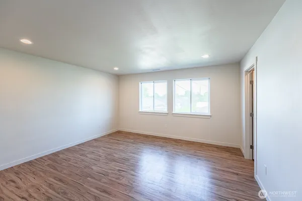 a view of an empty room with wooden floor and a window