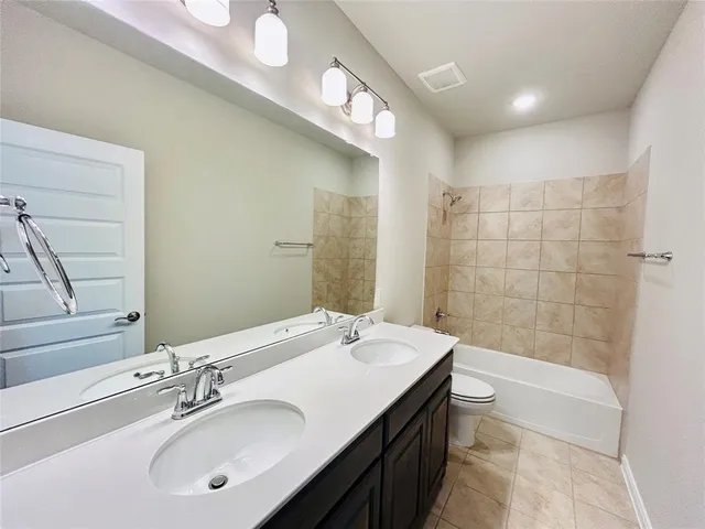 a bathroom with a double vanity sink large mirror and a bathtub
