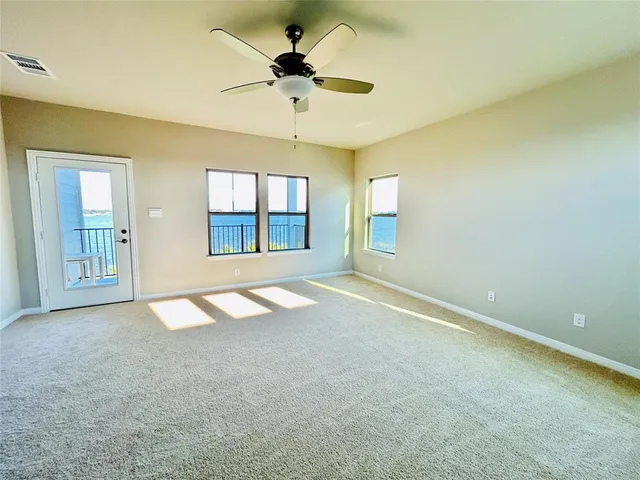 an empty room with windows and ceiling fan