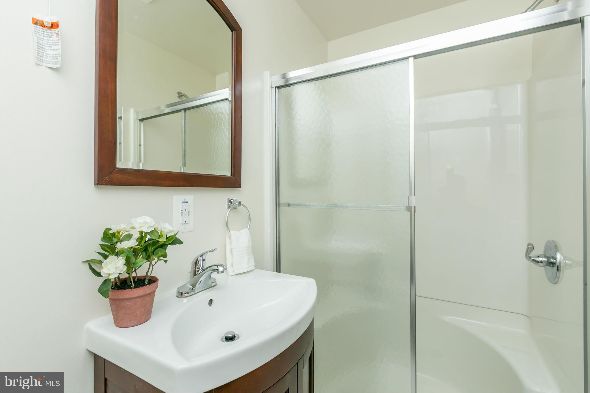 9302 Sea Point Road Baltimore, MD 21219 - Photo 22 of 30 a bathroom with a sink a mirror and a shower