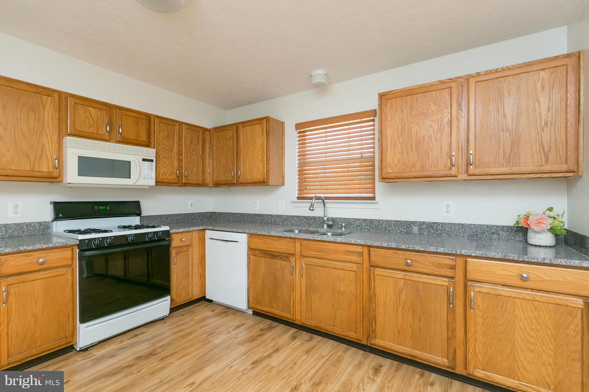 9302 Sea Point Road Baltimore, MD 21219 - Photo 7 of 30 a kitchen with granite countertop wooden cabinets stainless steel appliances and a window