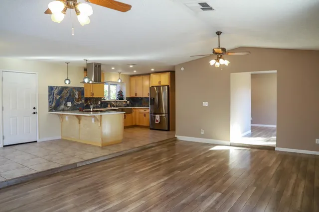 an empty room with wooden floor a chandelier fan a fireplace and windows