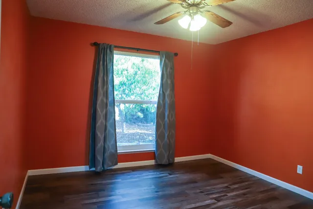 a view of an empty room with wooden floor and closet