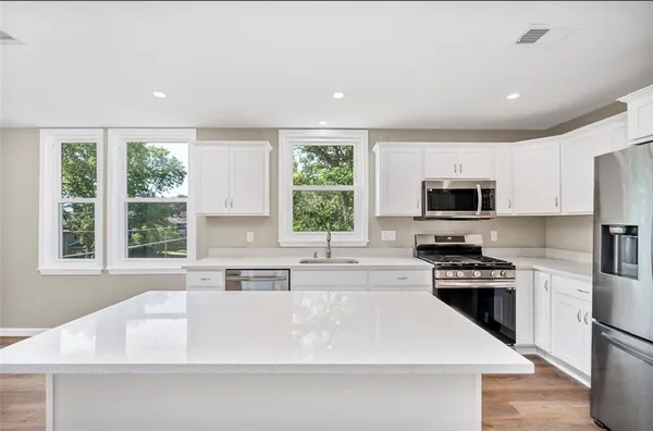 a large white kitchen with wooden floor a window and a sink