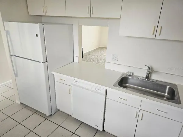 a kitchen with white cabinets and refrigerator