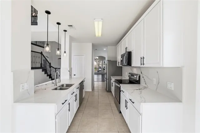 a large white kitchen with stainless steel appliances sink stove and cabinets