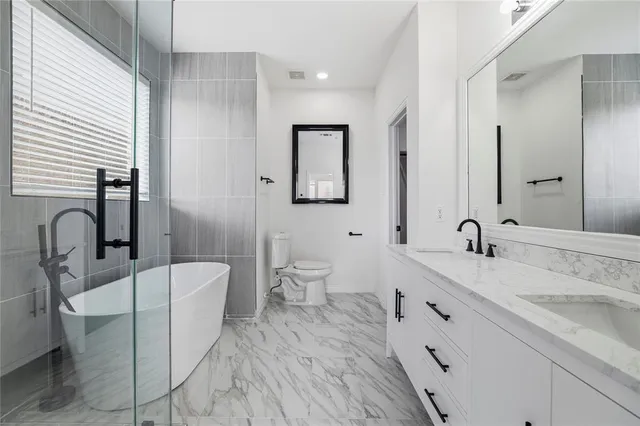 a spacious bathroom with a double vanity sink a mirror and a toilet