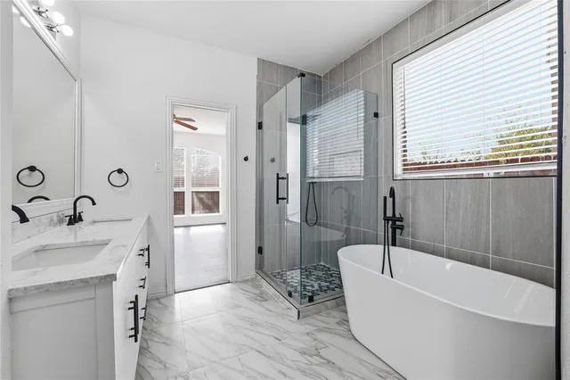 a bathroom with a bathtub a sink a window and a shower