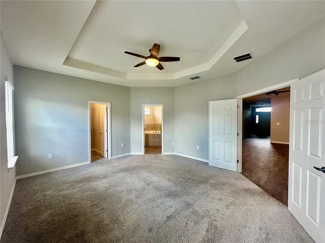 a view of an empty room with window and a ceiling fan