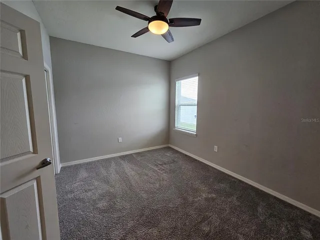 an empty room with windows and a ceiling fan