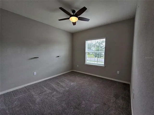 en empty room with windows and ceiling fan