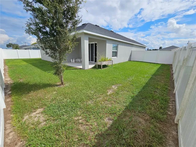 a view of a house with backyard and a tree