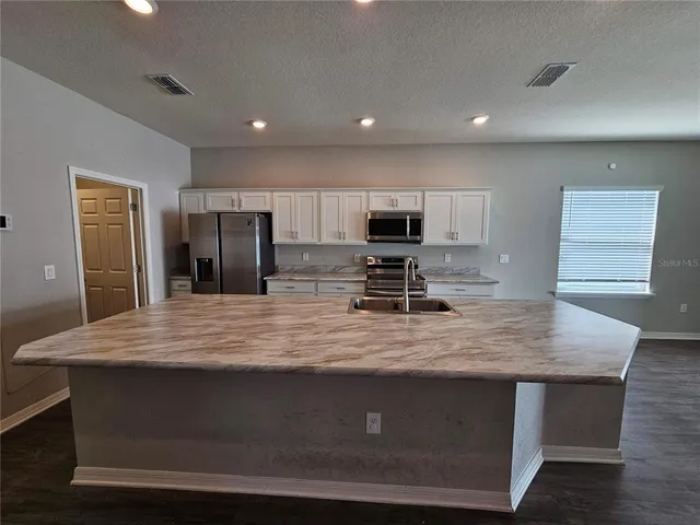 a kitchen with kitchen island stainless steel appliances and wooden cabinets