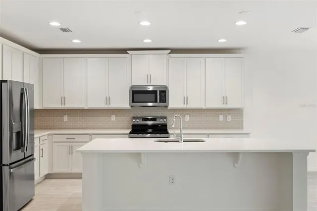 a kitchen with white cabinets and stainless steel appliances