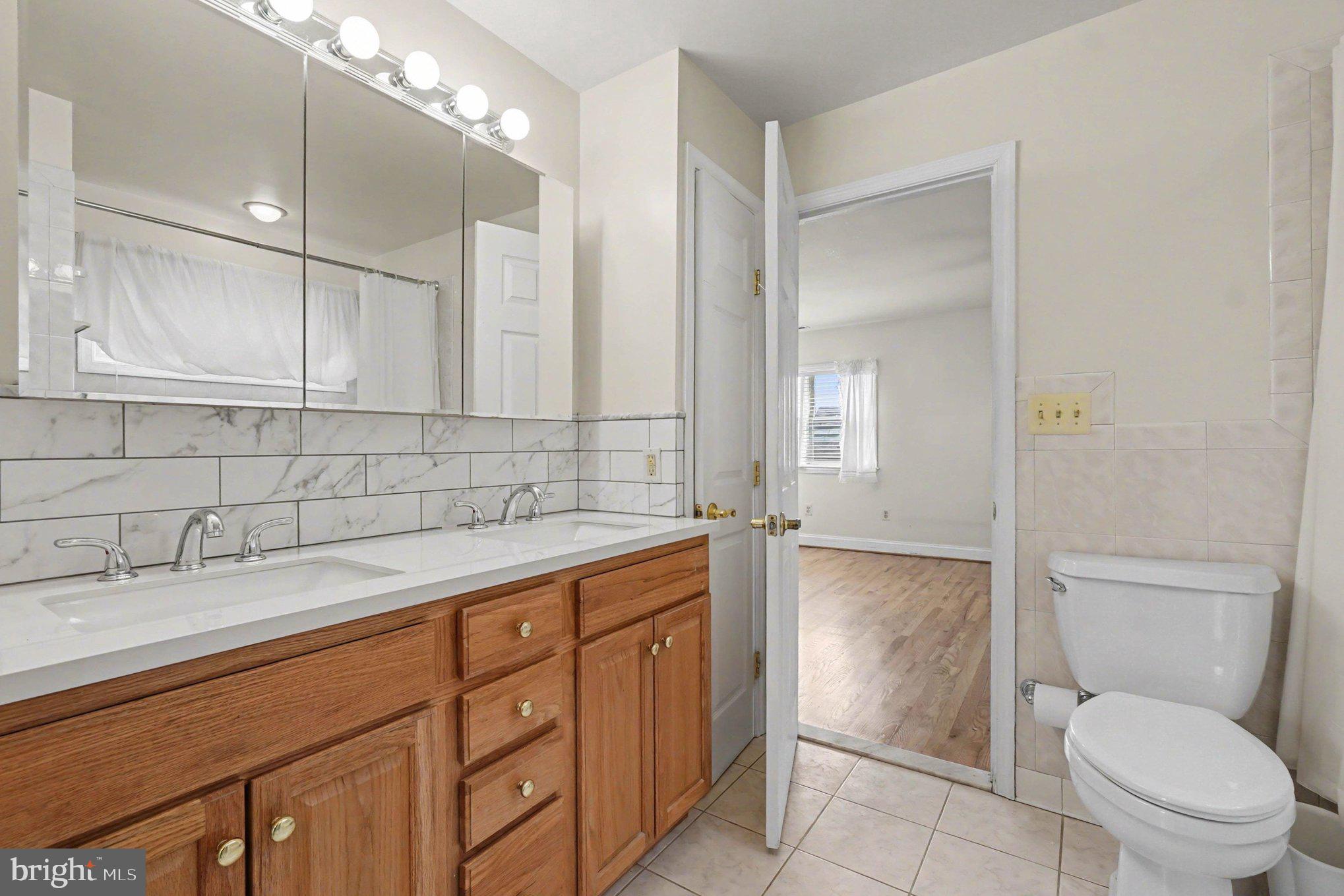 7908 Oakleigh Road Baltimore, MD 21234 - Photo 21 of 41 a bathroom with a granite countertop sink a toilet and mirror
