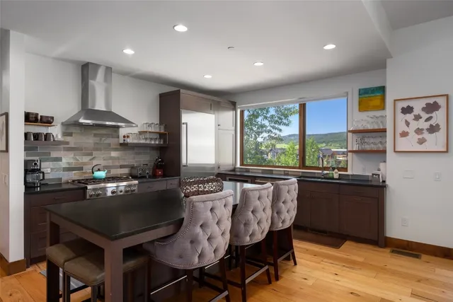 a kitchen with stainless steel appliances granite countertop a sink a stove a refrigerator dining table and chairs