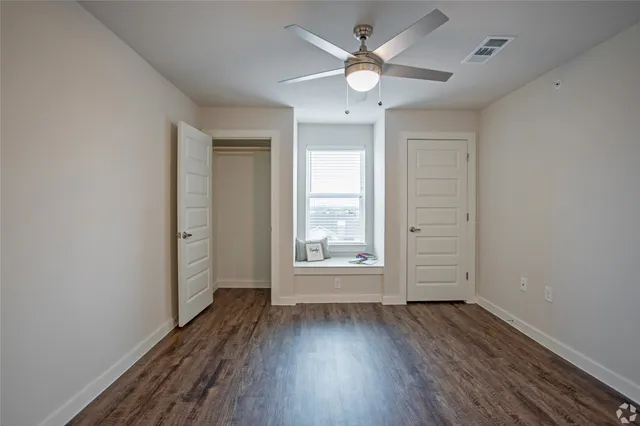an empty room with wooden floor and windows
