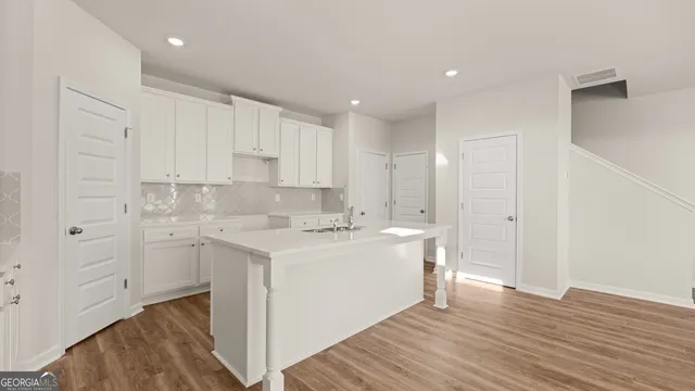 a view of a kitchen with white cabinets and wooden floor
