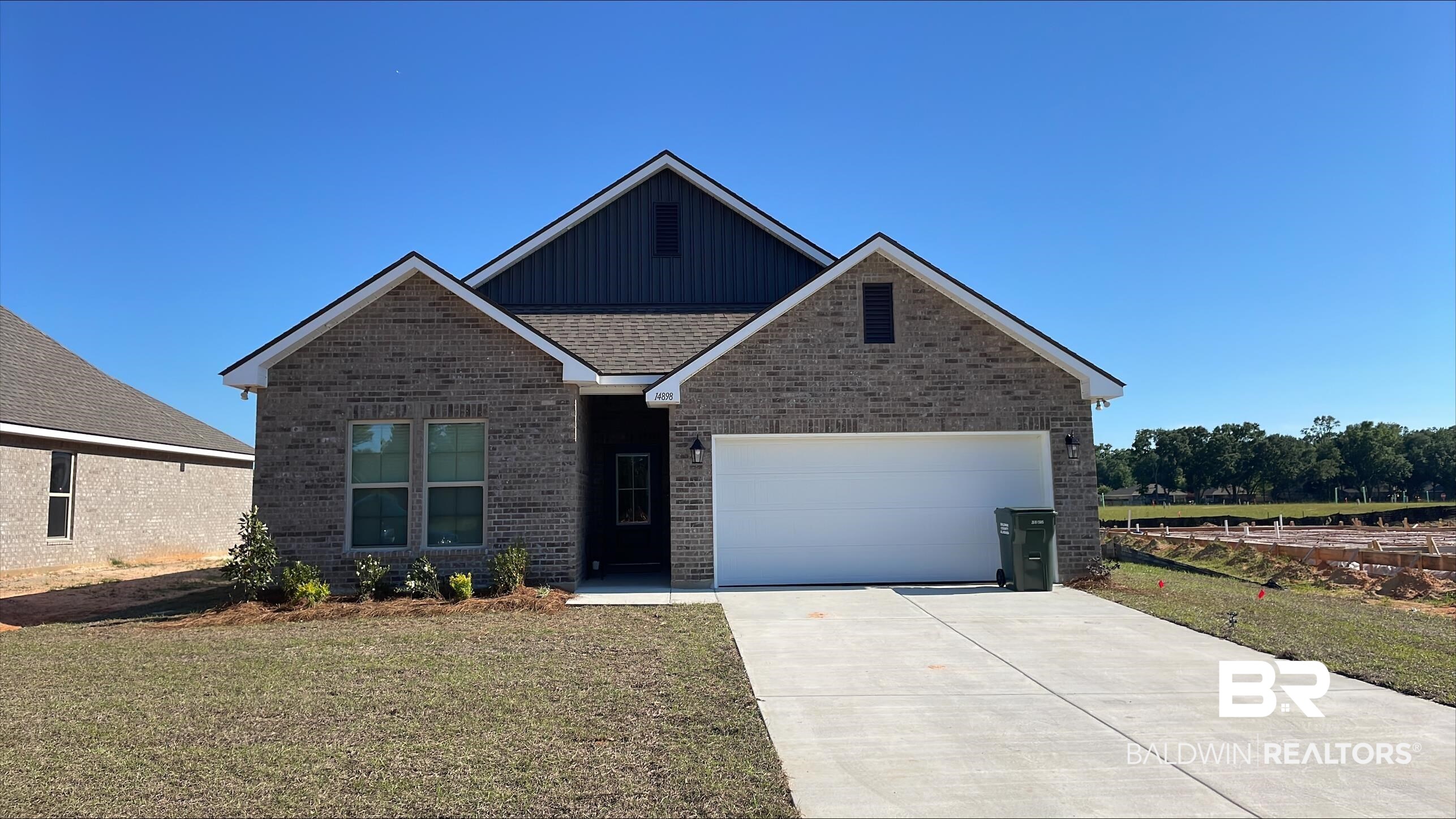 14898 Arrowhead Court Silverhill, AL 36576 - Photo 1 of 3 Contemporary brick exterior featuring a dark vertical siding accent, two-car garage, concrete driveway, and front landscaping