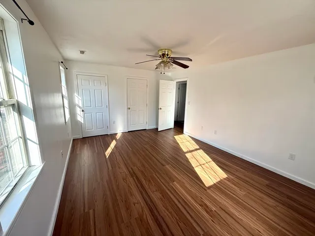 a view of empty room with wooden floor and fan