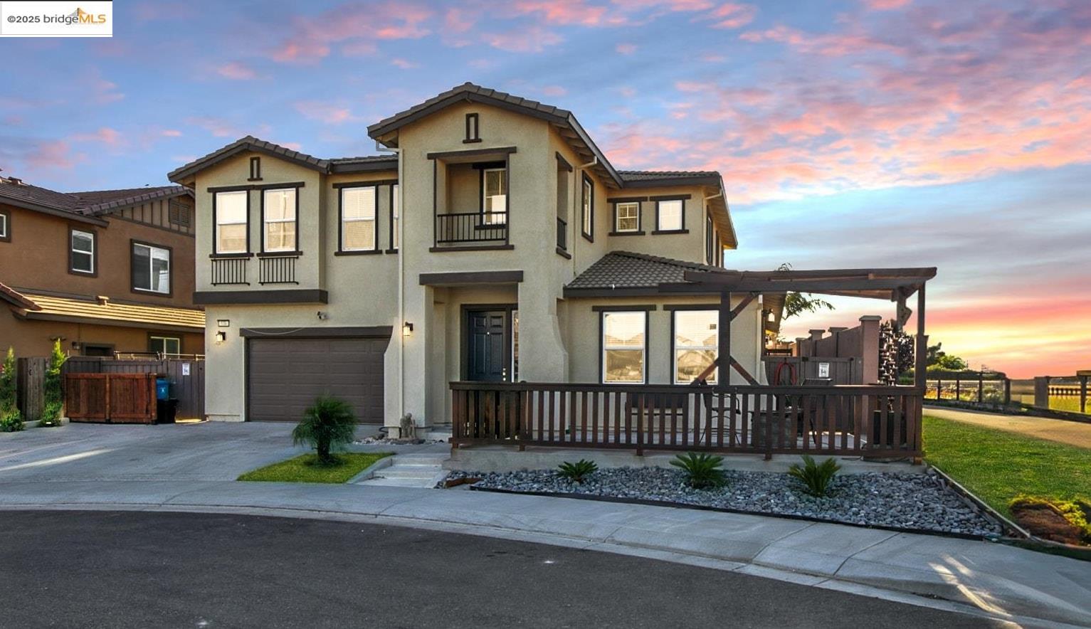 View of front of property with driveway, an attached garage, stucco siding, a balcony, and a tiled roof