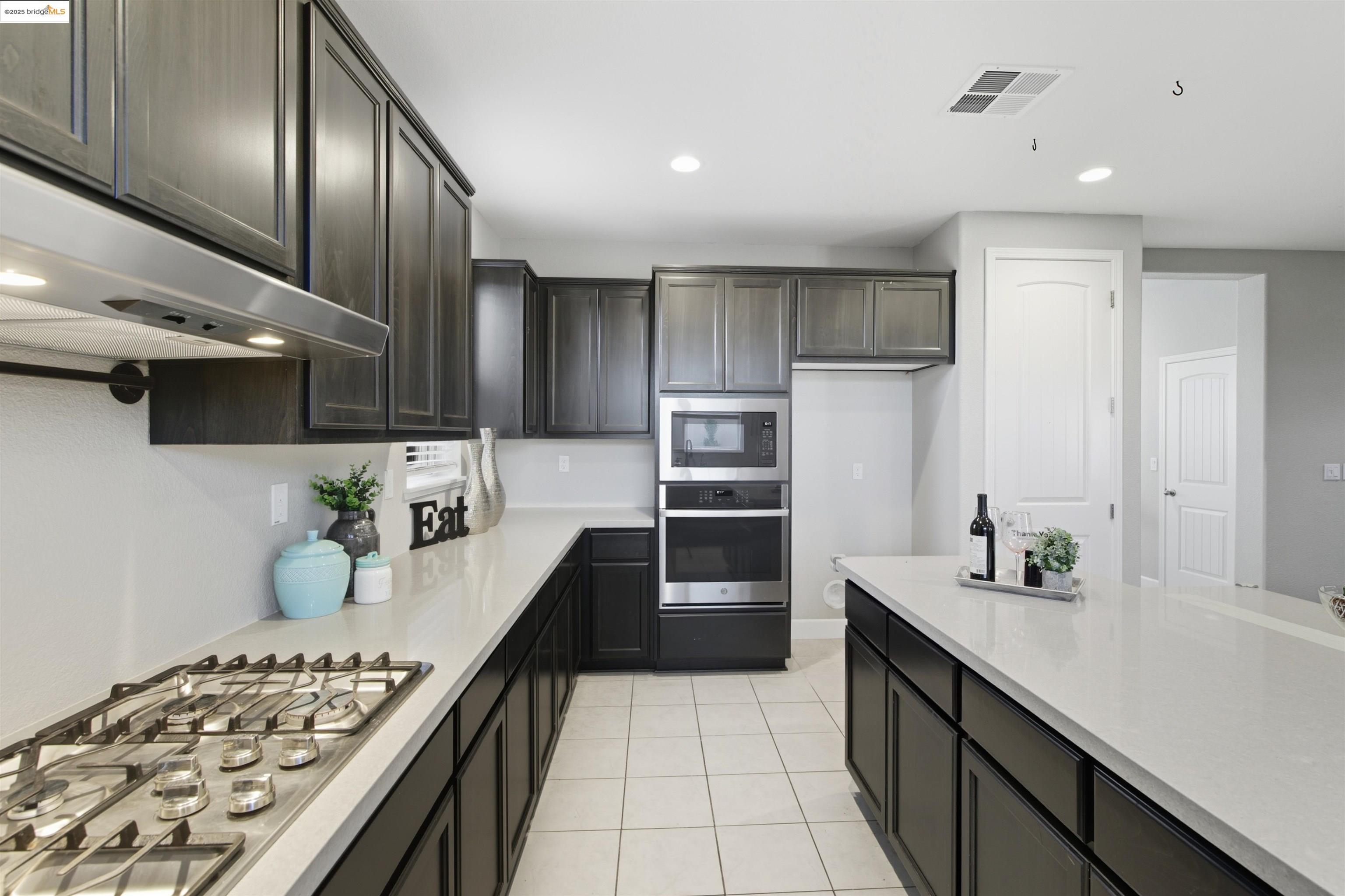 536 Aster Street Vacaville, CA 95688 - Photo 22 of 53 Kitchen with appliances with stainless steel finishes, recessed lighting, light tile patterned flooring, under cabinet range hood, and light stone countertops