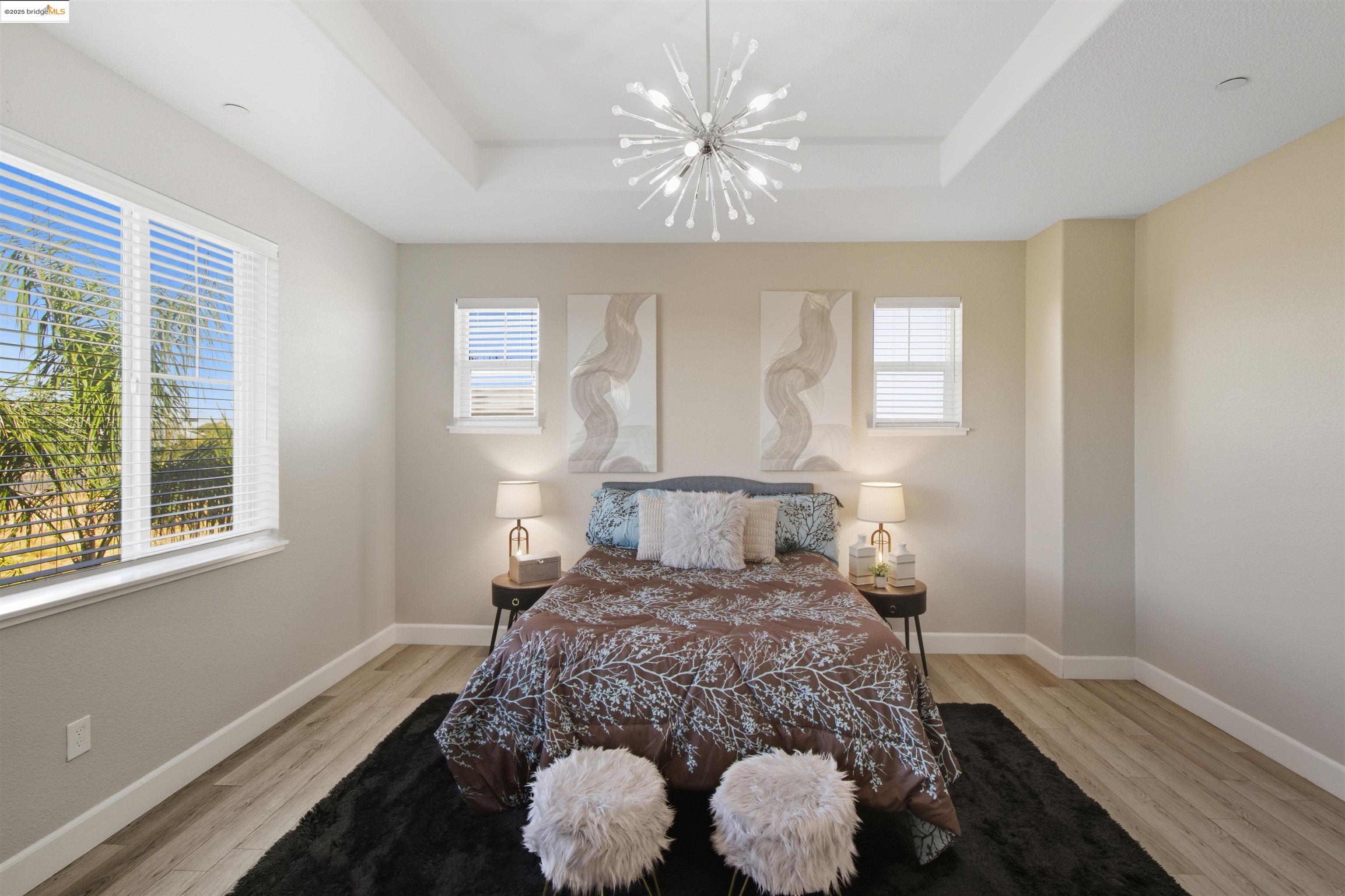 536 Aster Street Vacaville, CA 95688 - Photo 28 of 53 Bedroom with a raised ceiling, a chandelier, light wood-style flooring, and multiple windows