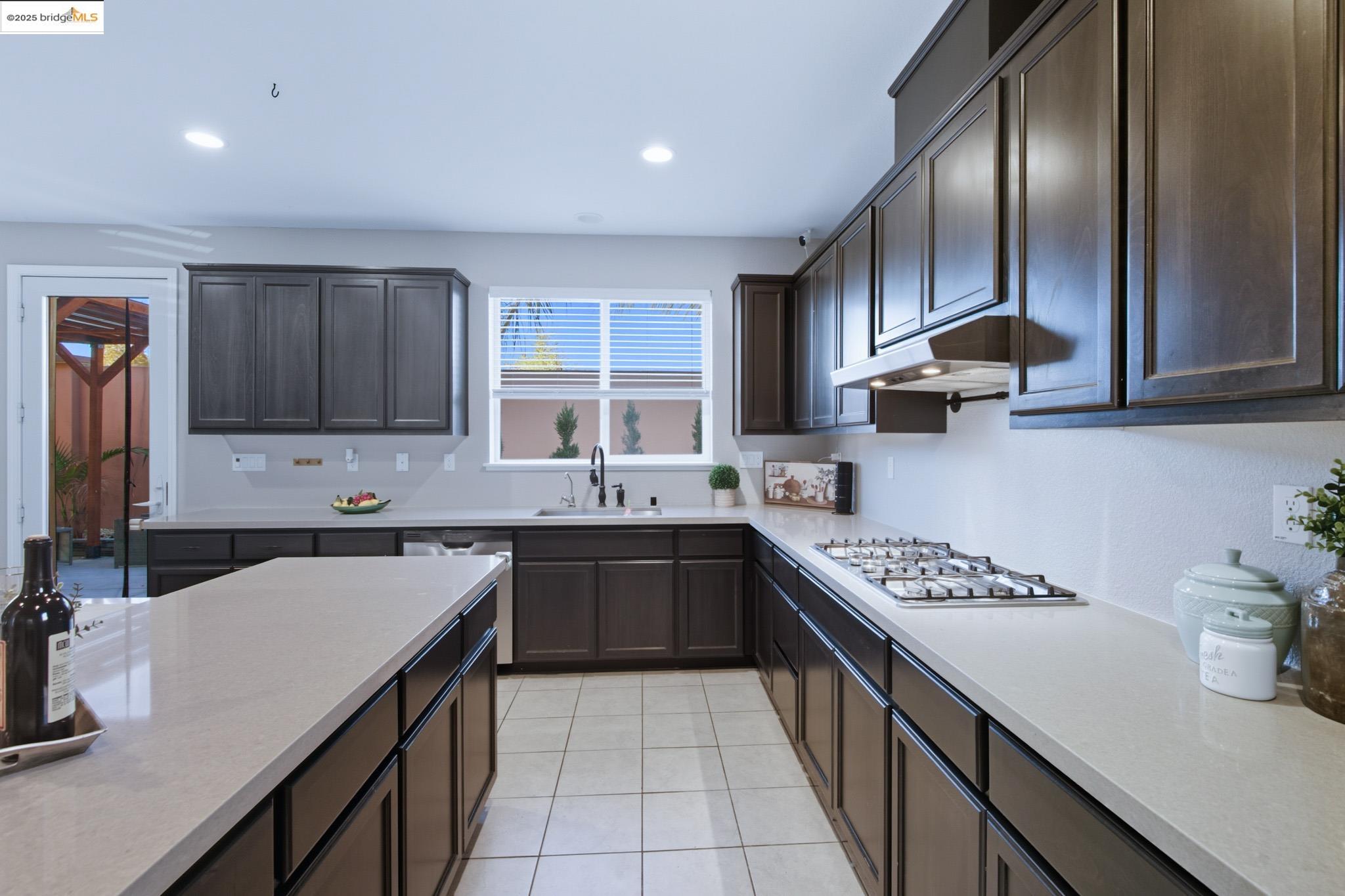 536 Aster Street Vacaville, CA 95688 - Photo 44 of 53 Kitchen with dark brown cabinets, light tile patterned flooring, light stone countertops, recessed lighting, and stainless steel appliances