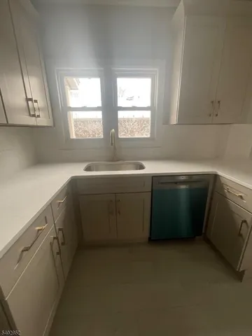 a utility room with stainless steel appliances a sink stove and cabinets