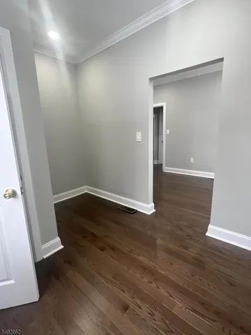 an empty room with wooden floor and mirror