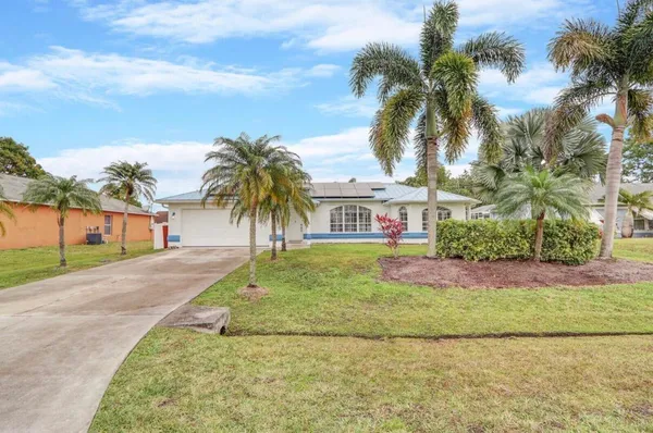 front view of house with a yard and palm trees