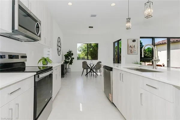 a living room with furniture a chandelier and a view of kitchen
