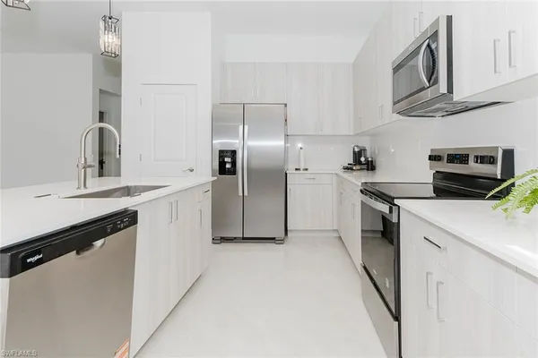 a kitchen with stainless steel appliances granite countertop a sink a stove a refrigerator a washer and dryer