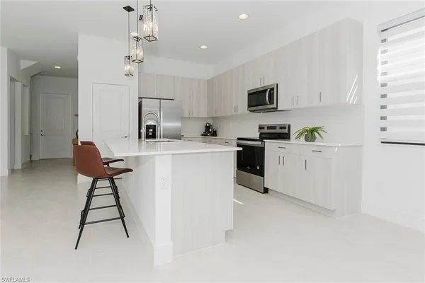 a kitchen with stainless steel appliances kitchen island a refrigerator sink and white cabinets