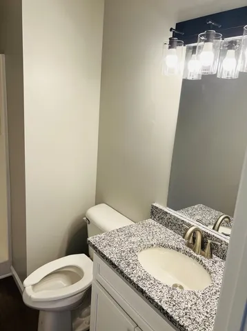 a bathroom with a granite countertop sink toilet and a mirror