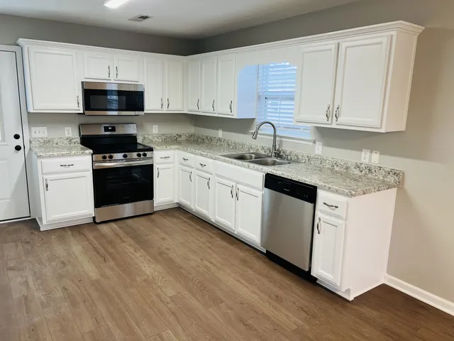 a kitchen with granite countertop white cabinets and stainless steel appliances