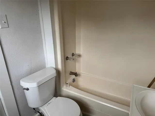 a white toilet sitting next to a bath tub