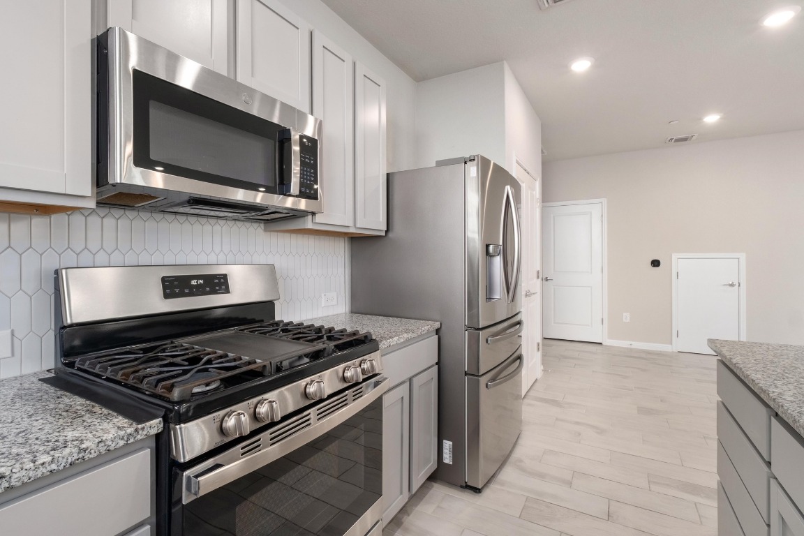 9015 Cattle Baron Path, Unit 1905 Austin, TX 78747 - Photo 12 of 40 a kitchen with stainless steel appliances granite countertop a stove a refrigerator and a microwave