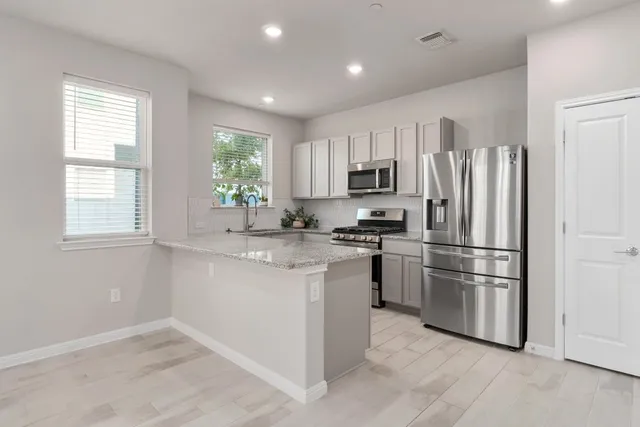 a kitchen with stainless steel appliances granite countertop white cabinets a sink and a stove