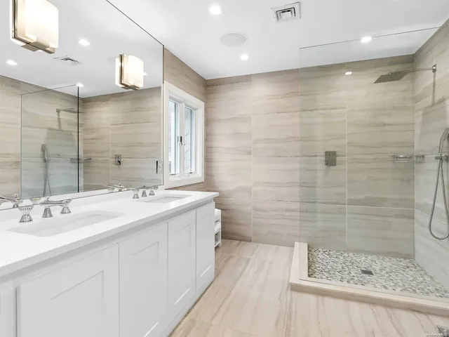 a bathroom with a double vanity sink mirror and shower