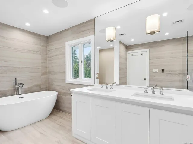 a bathroom with a double vanity sink mirror and bathtub