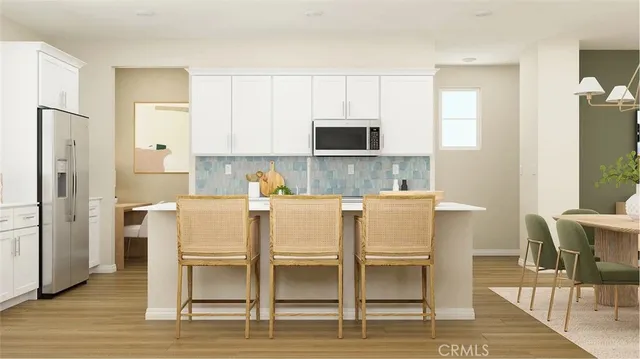 a white kitchen with wooden floor and stainless steel appliances