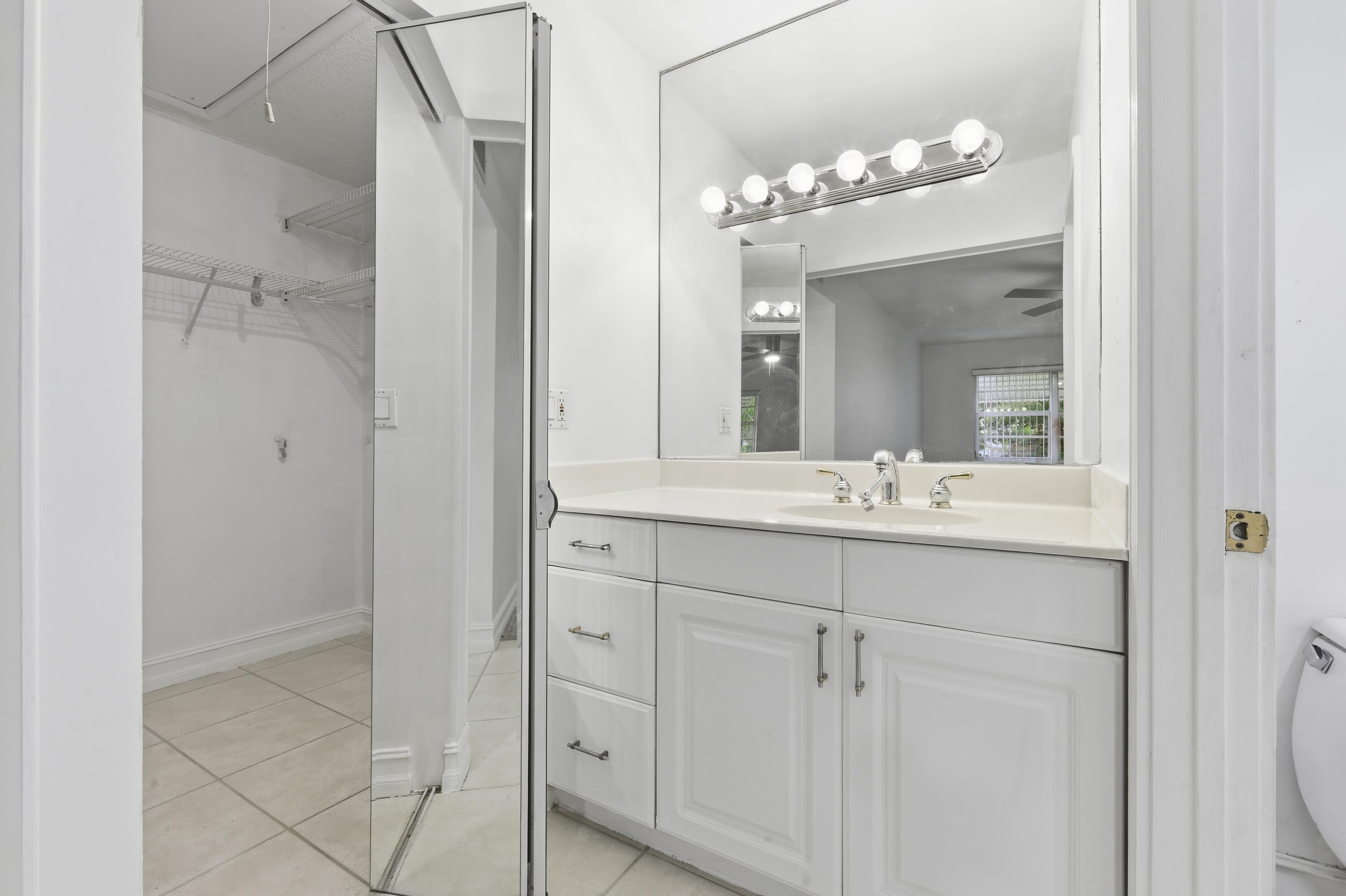1167 South Drive Circle, Unit D Delray Beach, FL 33445 - Photo 13 of 26 a bathroom with a double vanity sink and mirror