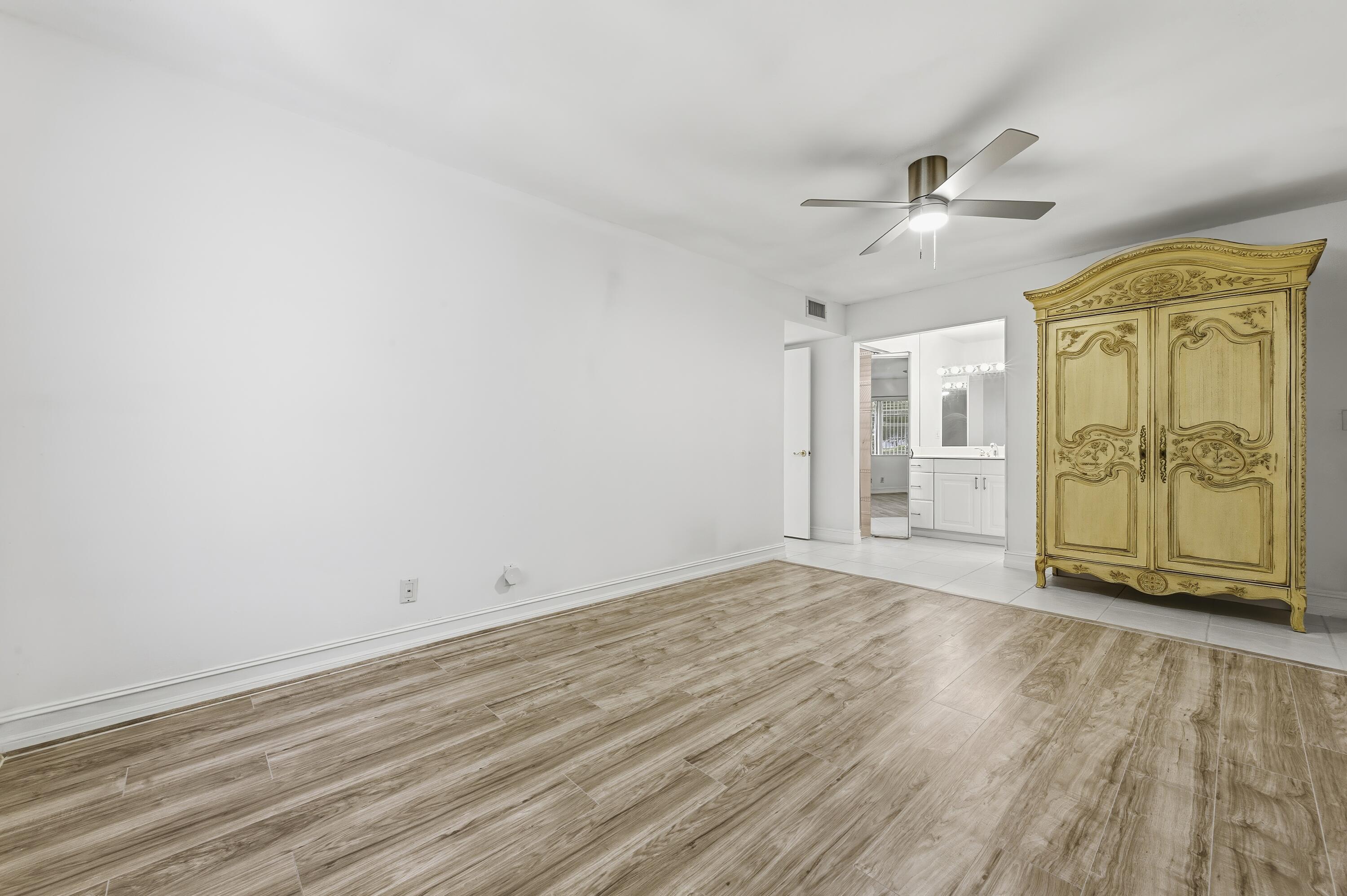 1167 South Drive Circle, Unit D Delray Beach, FL 33445 - Photo 17 of 26 an empty room with wooden floor fan and windows
