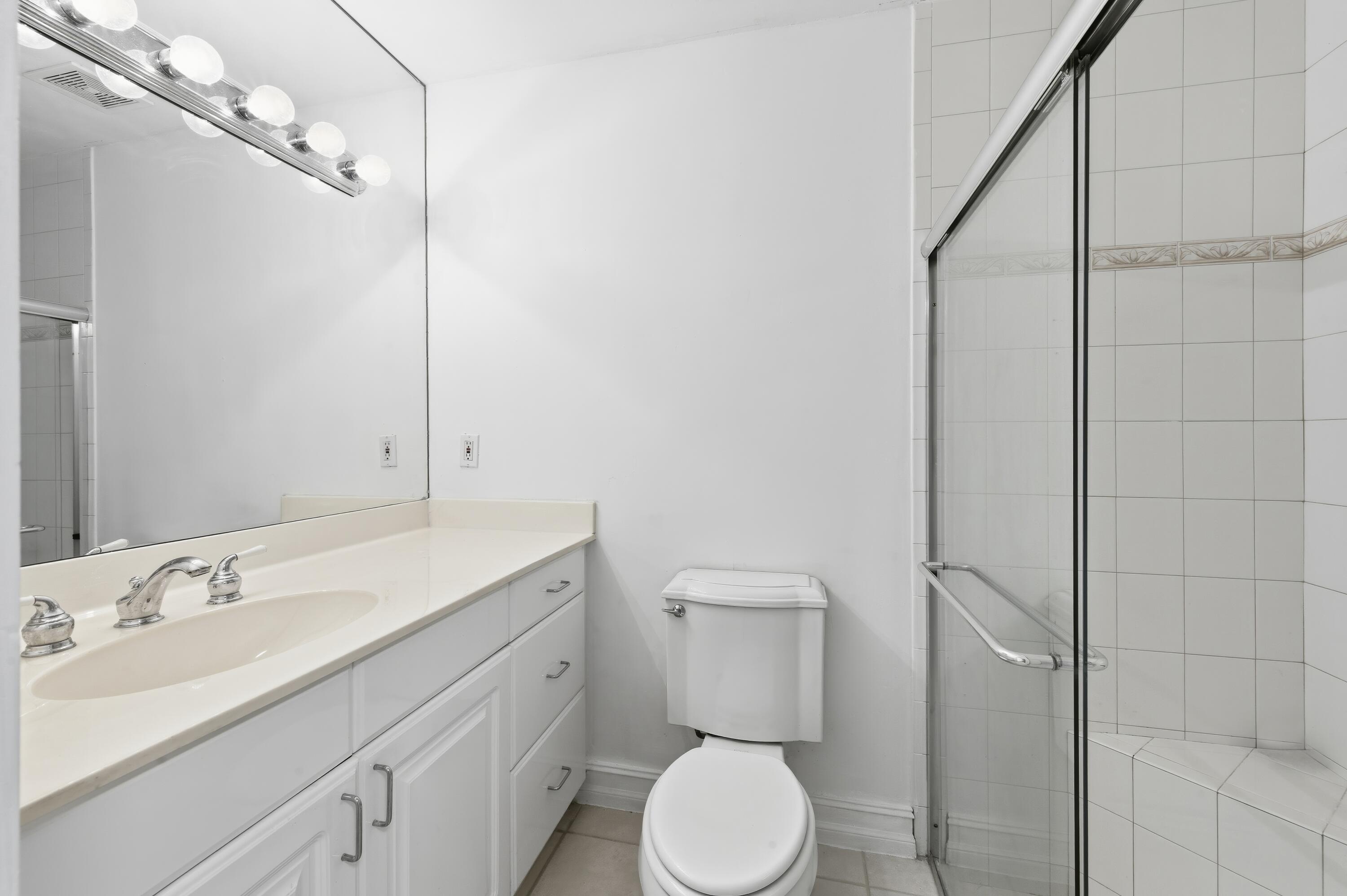 1167 South Drive Circle, Unit D Delray Beach, FL 33445 - Photo 10 of 26 a bathroom with a toilet a sink and mirror